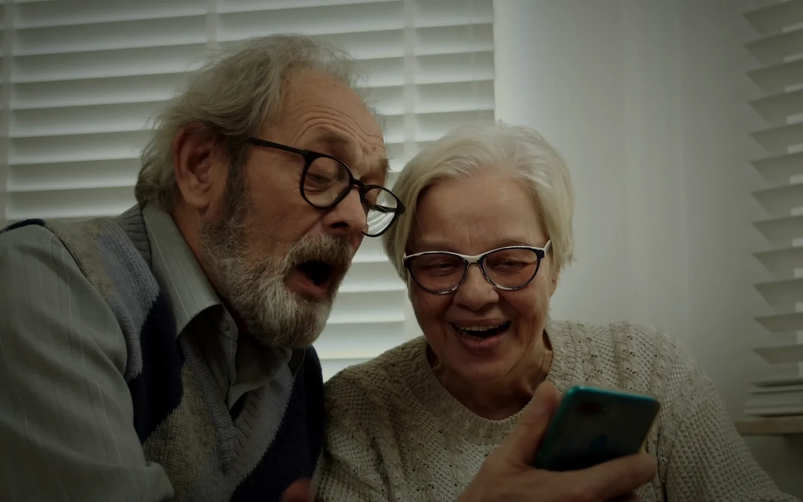 Parents smiling at a phone as money arrives